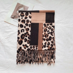 Close-up of leopard print and geometric patchwork scarf with soft tassel details