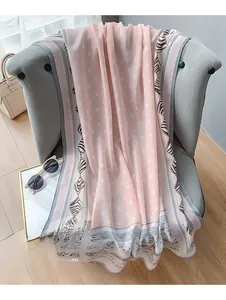 Détail d'une écharpe en lin rose à pois blancs avec bordure géométrique tissée sur une chaise