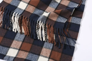 Detail of classic plaid pattern scarf with soft tassels in brown and navy blue tones