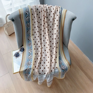 Détail d'une écharpe en lin beige à pois marrons et motif zèbre sur une chaise en velours