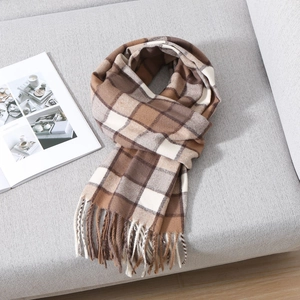 Classic earth-toned plaid scarf with soft fringe tassels on a cozy grey sofa