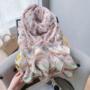 Détail d'une écharpe légère en coton et lin avec pois oranges et motifs ethniques