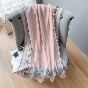 Écharpe de mode rose à pois en coton et lin avec bordures zébrées drapée sur un fauteuil