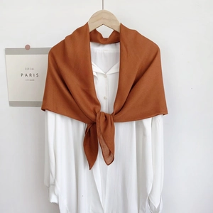 Caramel brown cotton linen shawl hanging on a wooden hanger with a white shirt