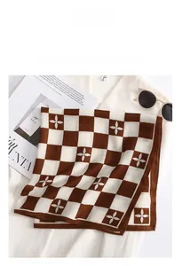 Flat lay of brown and beige checkerboard silk scarf with floral patterns on white shirt