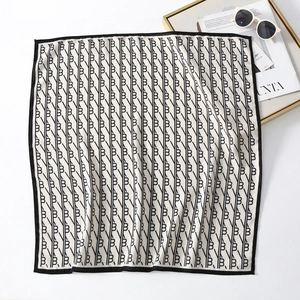 Detail of elegant black and white silk scarf with letter B print and sunglasses accessory