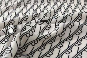 Macro detail of twill fabric silk scarf featuring geometric patterns and letter prints