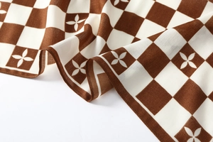 Close-up of velvet scarf with brown checkerboard pattern and four-petal star motifs