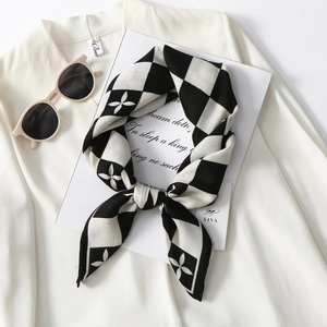 Detail of checkered velvet scarf with clover pattern displayed on a white shirt