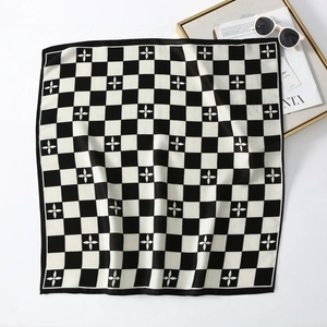 Close-up of black and white checkerboard velvet scarf with floral pattern and accessories