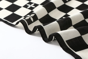 Detailed view of black and white checkerboard velvet scarf with subtle clover patterns