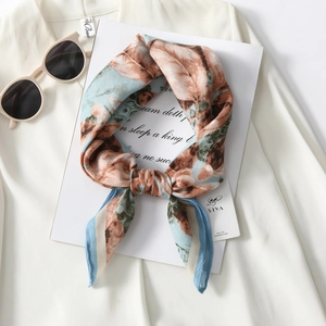 Elegant floral print square scarf in light blue and brown, styled as a chic knotted necktie