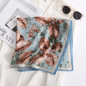 Elegant floral square silk scarf in light blue with realistic leaf print on a white blazer