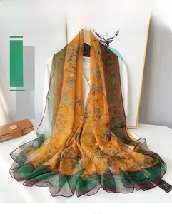 Detail of warm orange beach scarf with bamboo leaf patterns and green border