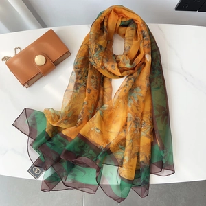 Detailed macro view of daisy floral print on soft chiffon scarf and branding tag detail