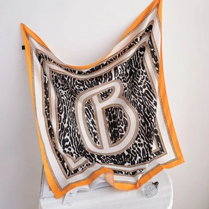 Détail du foulard en soie sergé avec motif léopard et bordure orange élégante