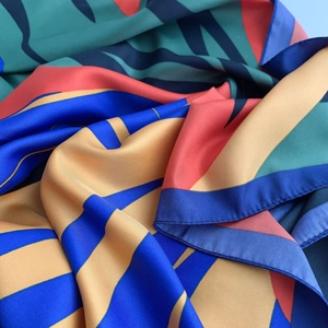 Detailed view of luxury twill silk scarf with bold geometric patterns and vibrant colors