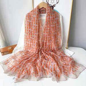 Detail of the elegant orange silk scarf with H-pattern hanging on a white shirt