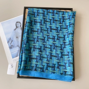 Close-up of blue and cyan geometric H-pattern summer shawl on a display tray