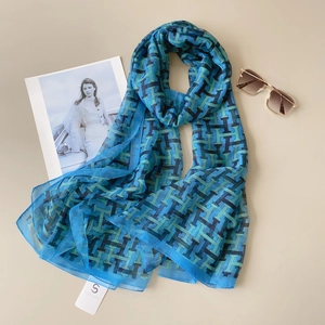 Detail of light blue geometric chiffon beach scarf with sunglasses and fashion magazine