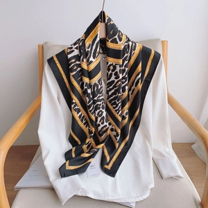 Détail d'un foulard en soie à imprimé léopard et chaîne dorée sur une chemise blanche