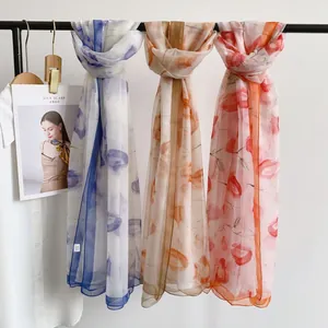 Detail of floral chiffon scarves in blue, beige, and orange hanging on a rack