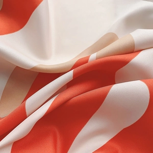 Detailed close-up of orange and white twill silk scarf showing high-gloss fabric texture