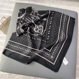 Detail of printed silk scarf with paisley pattern, gold chains, and tassel fringe
