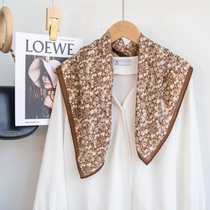 Detail view of the brown floral cotton scarf with white flowers on a wooden hanger