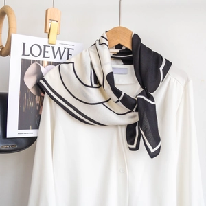 Dettaglio di un foulard in seta bianco e nero con stampa floreale su camicia e gruccia