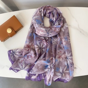 Detail view of purple floral chiffon scarf on marble background with elegant flat lay style