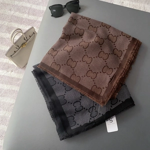 Detailed close-up of premium silk scarves with frayed edges and luxury logo pattern