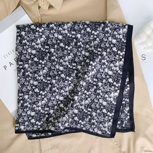 Black and white floral print cotton neck scarf displayed on a beige shirt with props