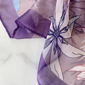 Close-up of lightweight purple floral silk scarf with fine edge stitching and sheer texture