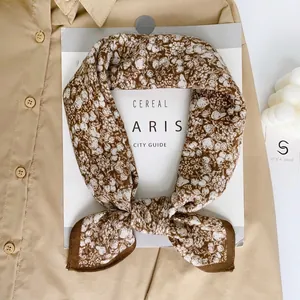 Floral cotton neck scarf in brown with white patterns styled on a khaki shirt