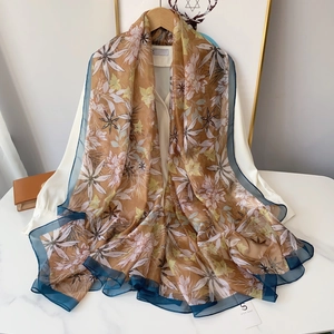 Close-up of floral print chiffon scarf with teal border on white shirt and marble surface