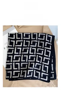 Detail of black geometric print square scarf on an apricot shirt with modern texture