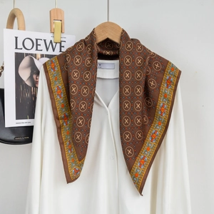 Close-up of geometric pattern silk scarf with vibrant orange border on a white shirt