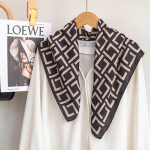 Close-up of geometric pattern scarf styled on a white shirt and wooden hanger