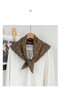 Close-up of a dark brown floral small square scarf tied on a white shirt collar