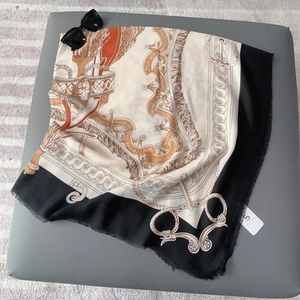 Detail of horse-themed silk square scarf featuring leather straps and fringe tassels