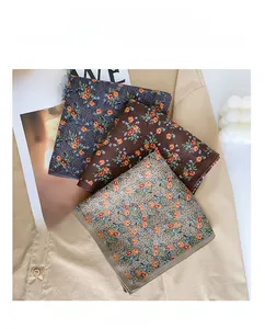 Detailed close-up of folded vintage floral silk scarves on neutral textile background