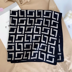 Modern black geometric pattern silk scarf styled on khaki shirt with chic lifestyle props