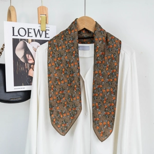 Detail view of brown floral scarf paired with a white shirt for a casual look