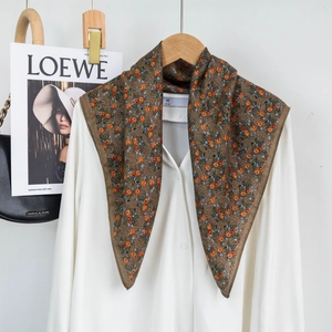 Detailed view of dark brown floral silk scarf with vintage orange pattern on white shirt