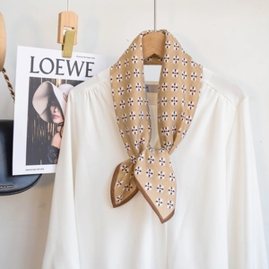 Detailansicht eines khakifarbenen Seidenschals mit geometrischem Blumenmuster auf Bluse