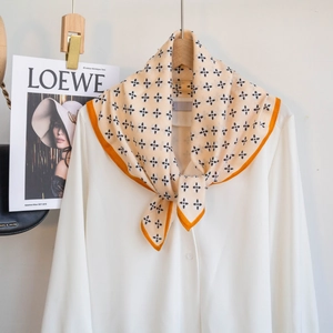 Detail eines bedruckten quadratischen Halstuchs mit orangefarbenem Rand auf Bluse