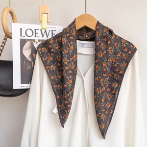 Close-up of floral print scarf in dark grey with orange flowers over a white shirt