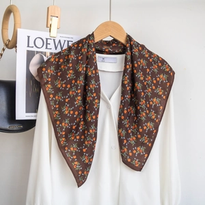 Detail of a brown floral silk scarf styled on a white shirt with vintage flower patterns
