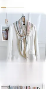Close-up of diamond-shaped silk scarf with letter patterns on a white blazer